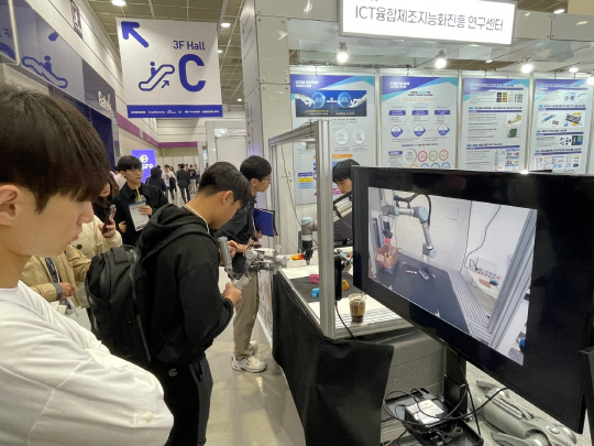 한국공학대학교 Grand-ICT센터 부스에서 협동로봇 시연을 관람 중인 참관객들. 모니터를 통해 로봇 작동 과정이 실시간으로 전시되고 있다.